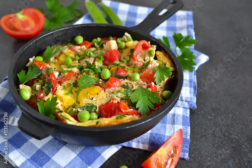 frittata with tomatoes, peppers, green peas and feta cheese in a