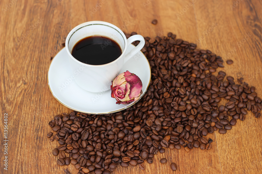 White Coffee mug with saucer and dried red rose and coffee beans on a wooden background closeup White Coffee mug with saucer and dried red rose and coffee beans on a wooden background closeup