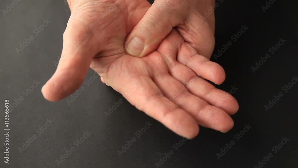 An older man rubs the soreness in his hand. An older man rubs the soreness in his hand.