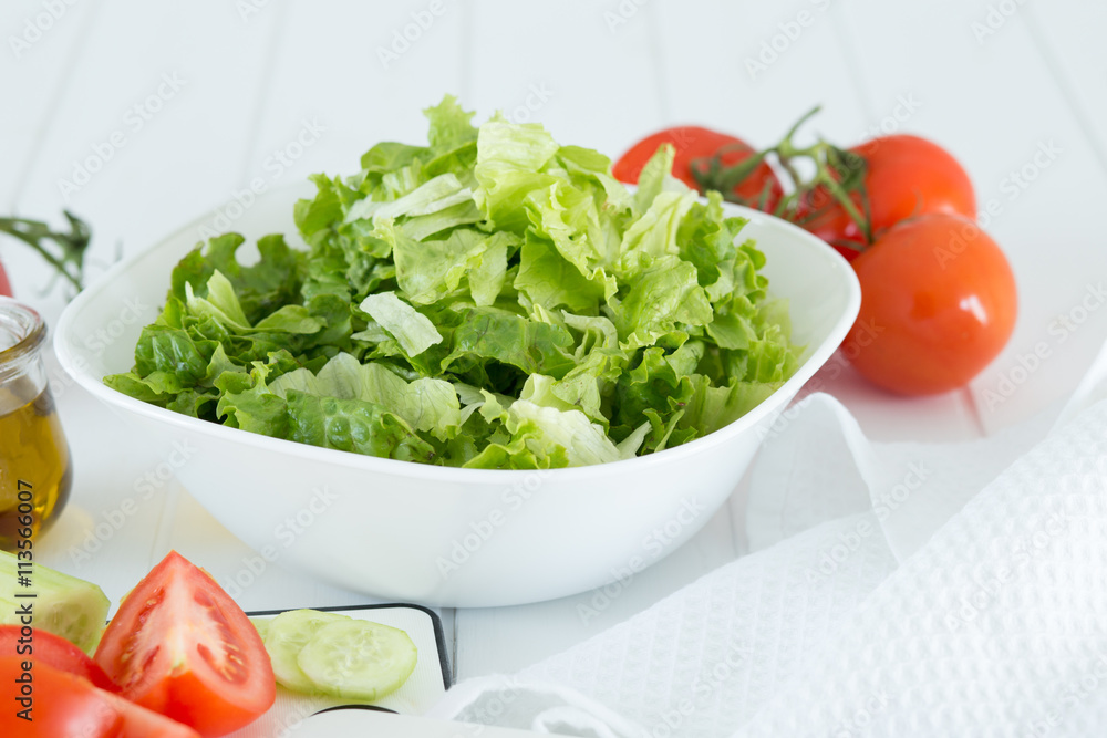 Preparing a healthy fresh salad with tomato, lettuce, cucumber and oil Preparing a healthy fresh salad with tomato, lettuce, cucumber and oil