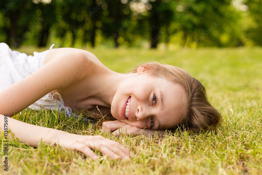 Portrait of a beautiful young girl lying on the grass outdoors in summer Portrait of a beautiful young girl lying on the grass outdoors in summer