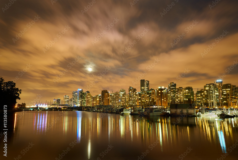 Moon Over Vancouver Night.  The night skyline of downtown Vancouver, British Columbia, Canada, from Stanley Park. Evening as the the moon is rising.
