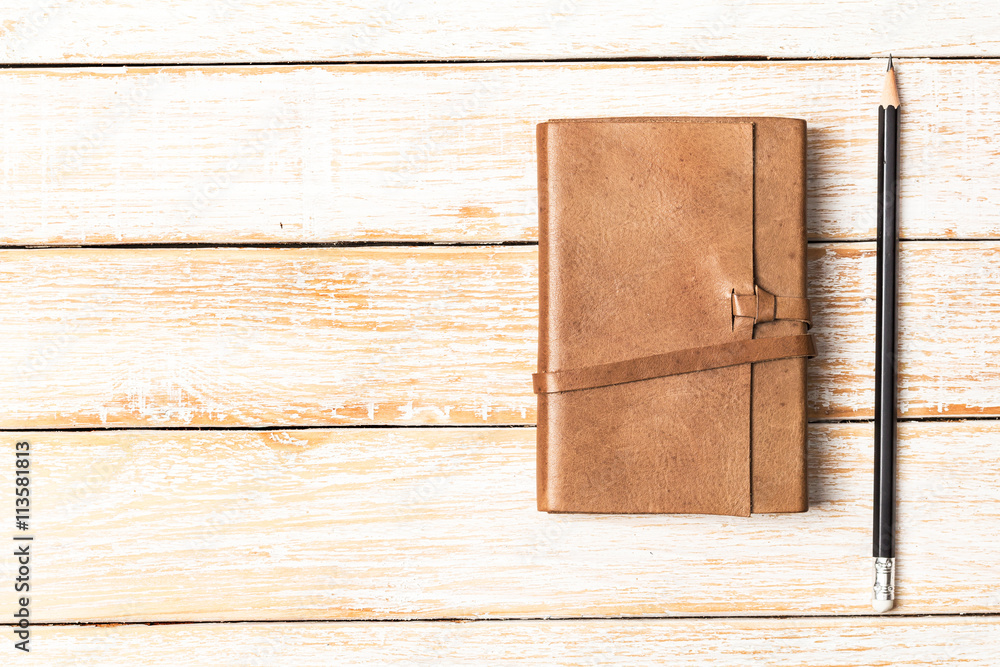 Fototapeta premium Leather diary notebook with pencil on white wooden background, B