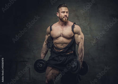 Powerful huge bodybuilder with dumbbells posing. © Fxquadro