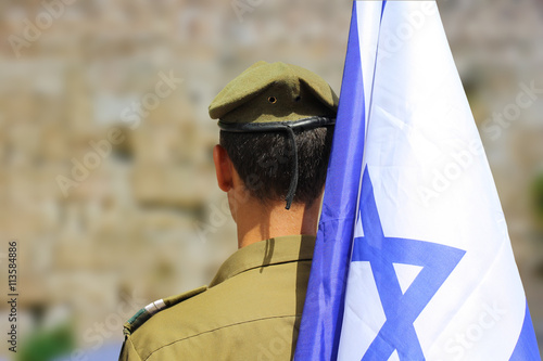 Vászonkép Israeli soldier with flag of Israel on blurred background of Western Wall