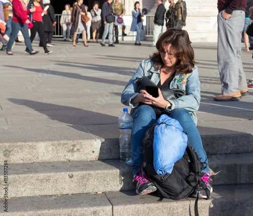 Woman sitting on the stairs reading a message on mobile phone photo