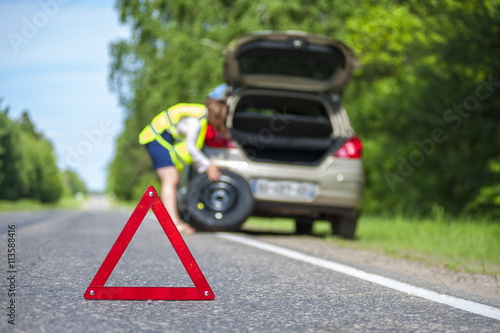 Woman changing tire after car breakdown