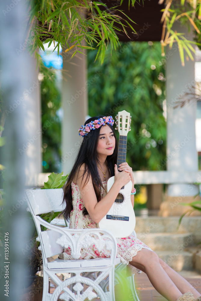 Fototapeta premium girl in a wreath of wild flowers with her guitar
