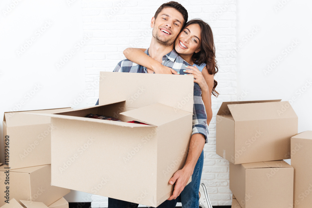 Smiling young couple carrying cardboard boxes and hugging Smiling young couple carrying cardboard boxes and hugging