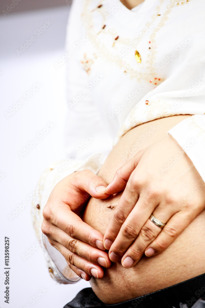 Pregnant woman creating heart shape with her hand
