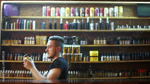 vape shop seller show e-cigarettes to buyer and exhaling smoke