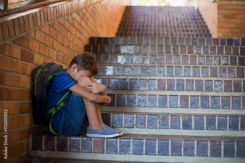 Sad schoolboy sitting alone on staircase