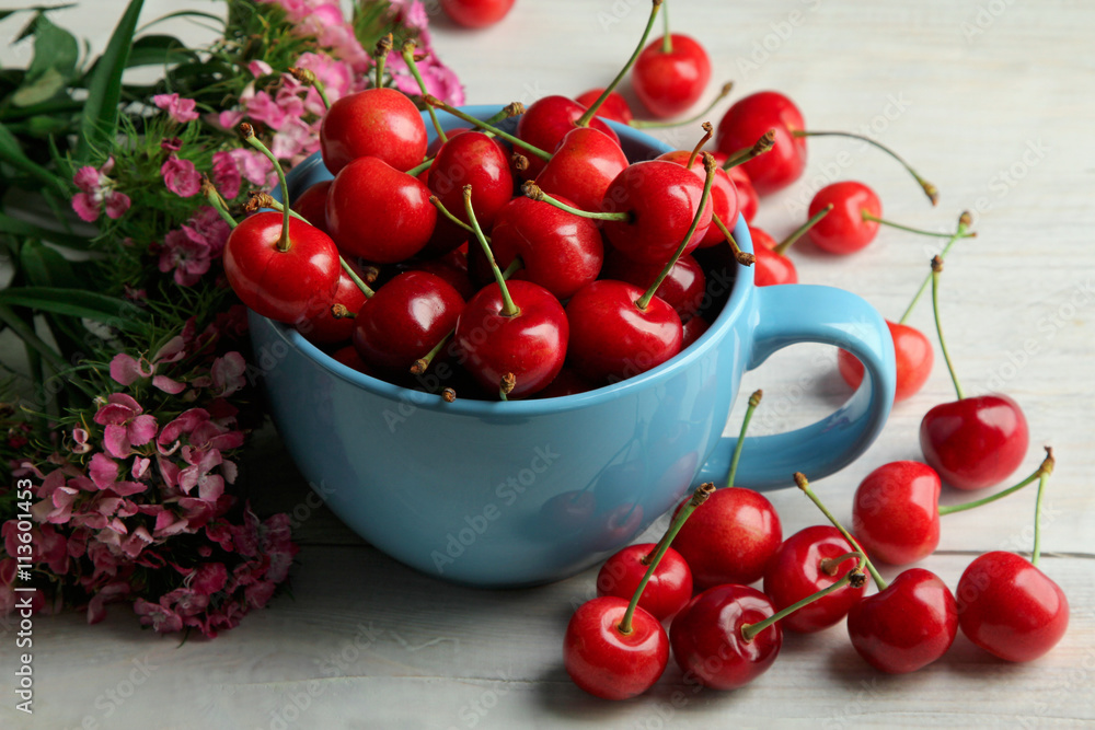 heap of sweet cherries in the bowl and scattered on a wooden background with flowers heap of sweet cherries in the bowl and scattered on a wooden background with flowers