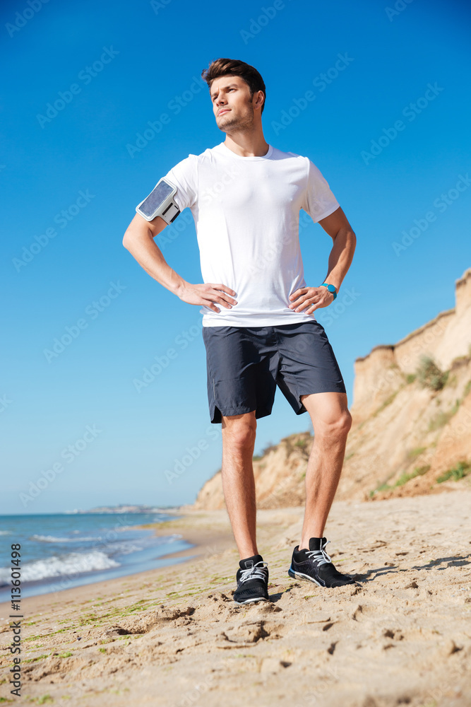 Attractive young sportsman with cell phone standing on the beach Attractive young sportsman with cell phone standing on the beach