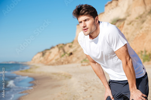 Handsome young man standing on the beach