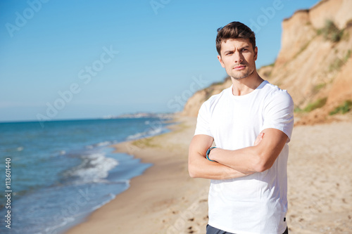 Serious young man standing on the beach