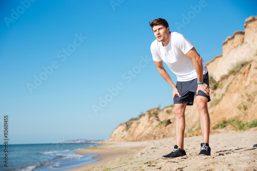 Handsome sportsman standing on the beach