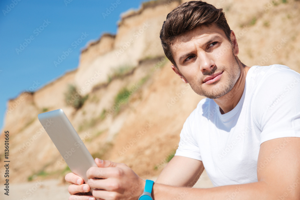 Handsome young man with tablet on the beach