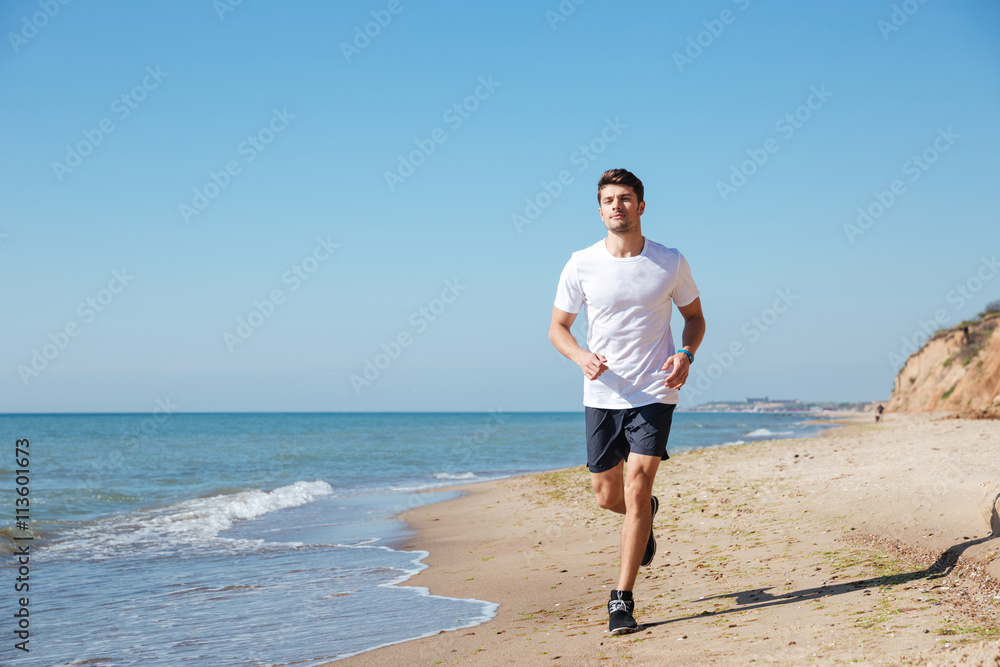 Happy sportsman running on the beach