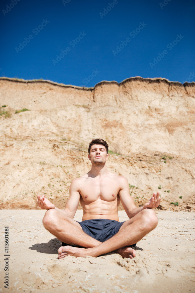 Man relaxing and meditating on the beach