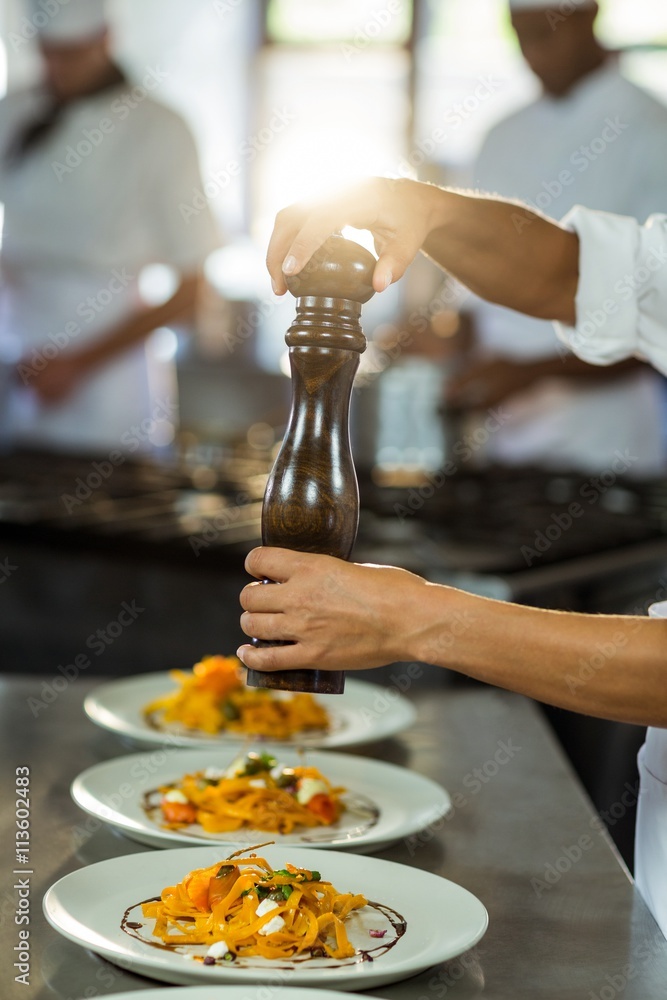 Fotobehang met Chef sprinkling pepper on a meal #113602483