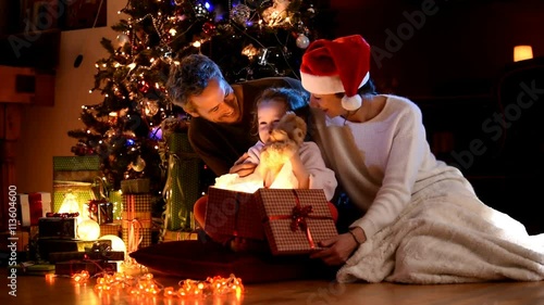a family near the Christmas tree, the girl finds a teddy bear in her gift box