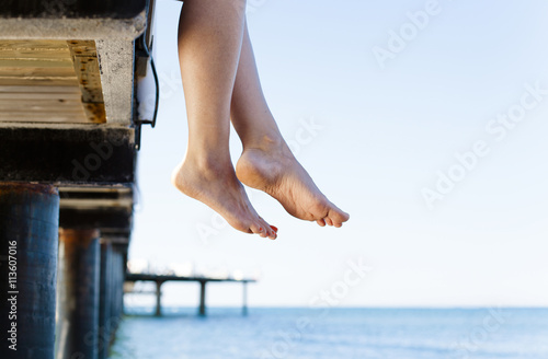 Woman's feet dangle from jetty
