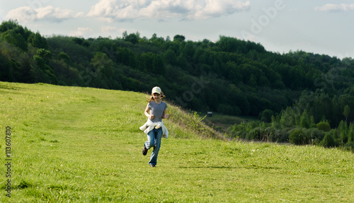 funny baby girl running on green field