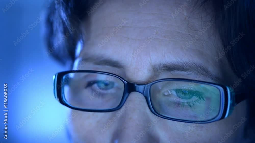 Closeup on one eye of a woman wearing glasses and looking at a computer screen. Closeup on one eye of a woman wearing glasses and looking at a computer screen.