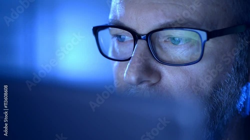 Closeup on one eye of a senior wearing glasses and looking at a computer screen.