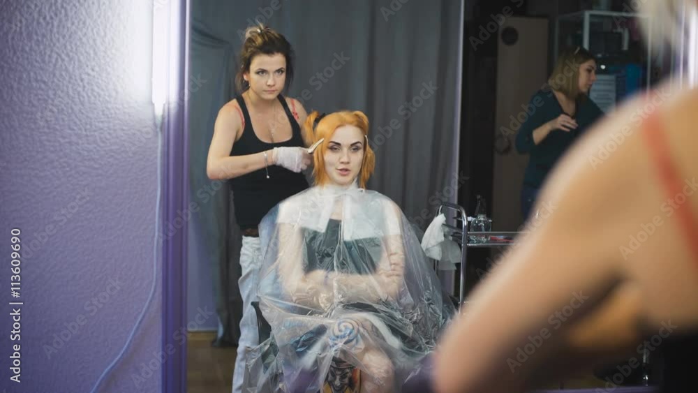 Professional hair coloring beauty studio. The girl in the client chair looking at reflection in the mirror. Professional hair coloring beauty studio. The girl in the client chair looking at reflection in the mirror.