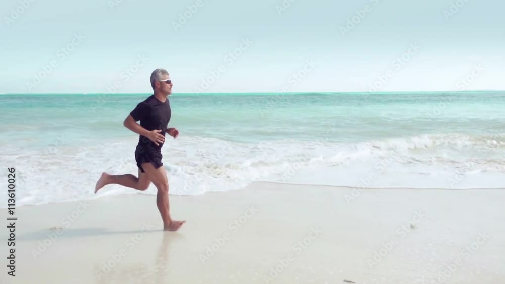 man in sport dress running on the beach steadicam shot 
