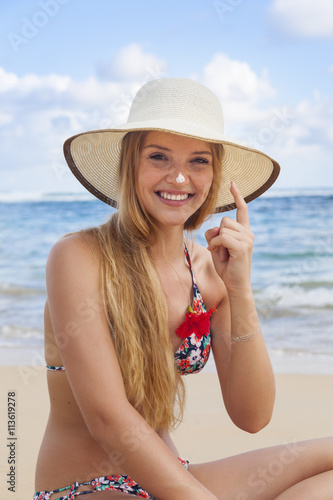 Young woman using sunscreen at beach photo