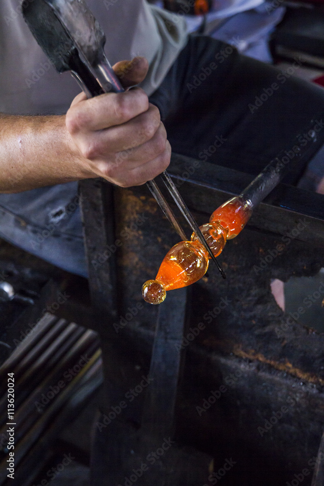 Man working with molten glass using a tweezers in a glass factory Man working with molten glass using a tweezers in a glass factory