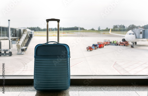 Suitcase at the airport, passenger airplane and luggage vehicle in the background photo