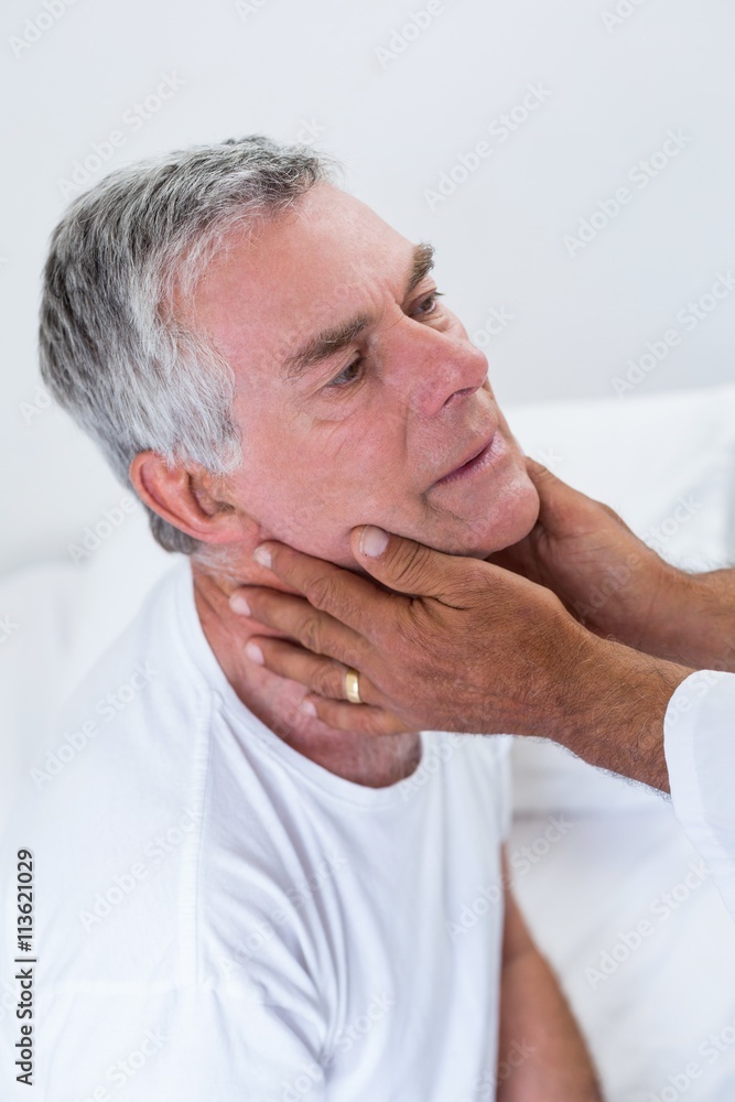 Obraz premium Male doctor examining senior mans neck
