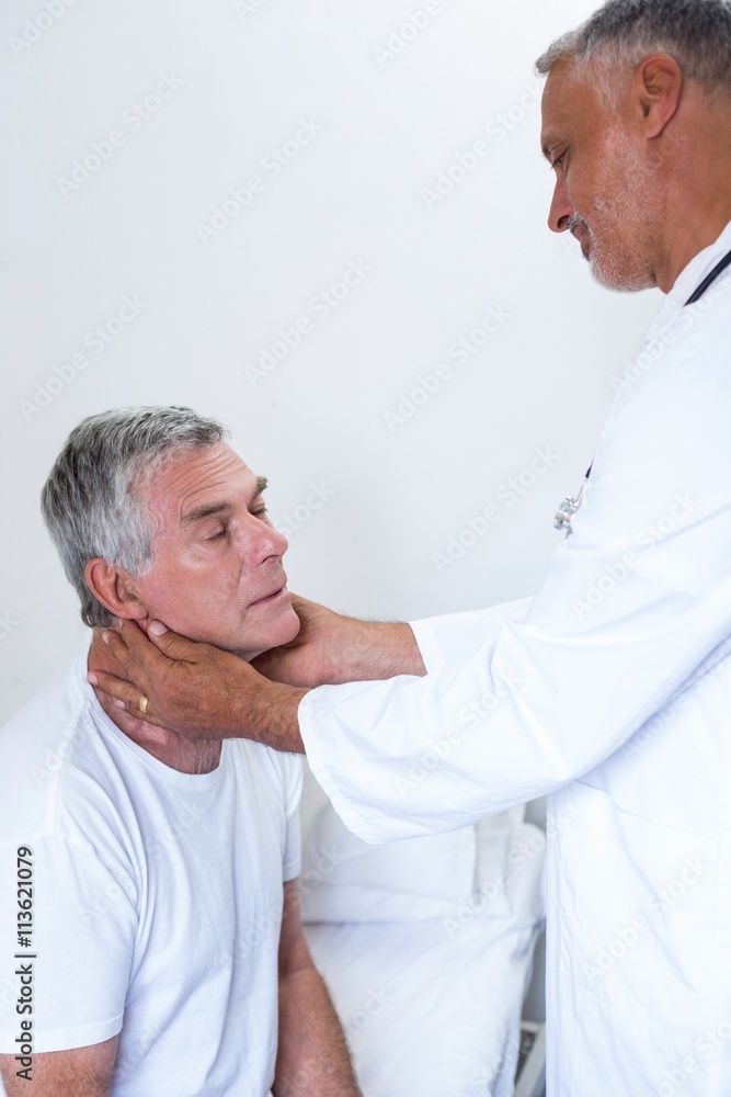 Obraz premium Male doctor examining senior mans neck