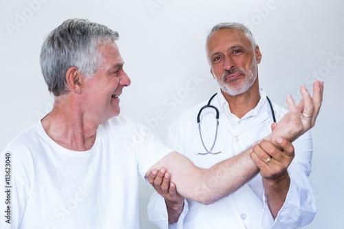 Male doctor giving palm acupressure treatment to senior man