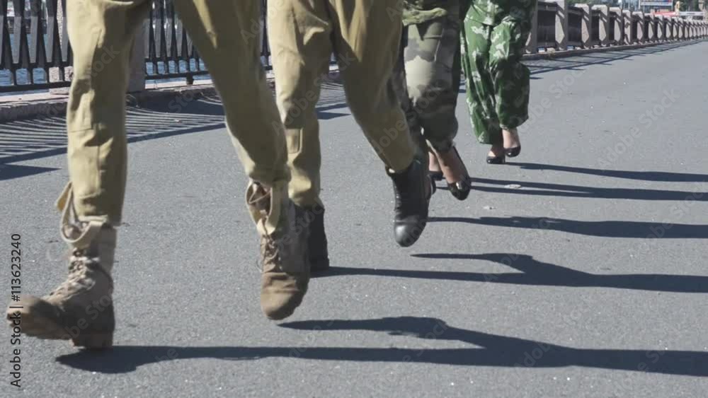 View of running male and female feet in military uniform on asphalt. Woman on heels. Sunny day. Seafront View of running male and female feet in military uniform on asphalt. Woman on heels. Sunny day. Seafront