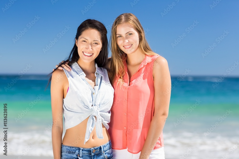 Young female friends standing on beach Young female friends standing on beach