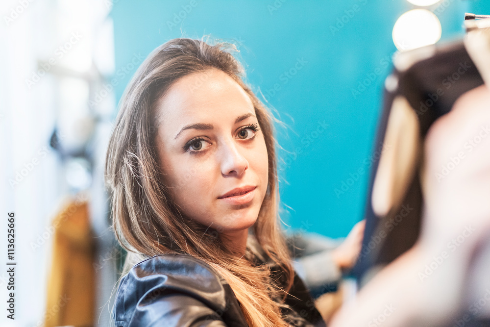 Beautiful young blonde woman looks at the clothes of a dress shop during a shopping day