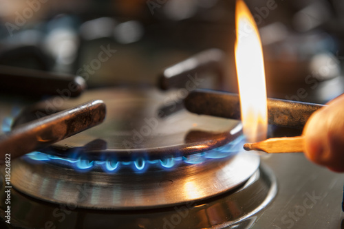 Картината върху платно A man lighting the gas-stove with a match