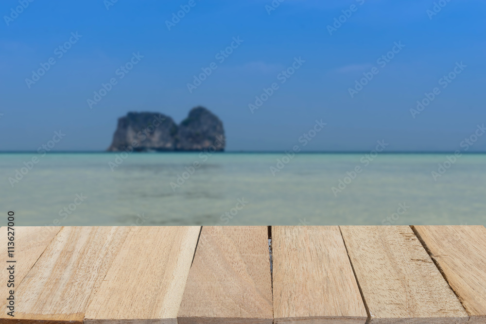 wood table top on blur of seascape and island on bluesky
