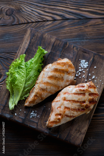Grilled chicken breasts with salad in a rustic wooden setting