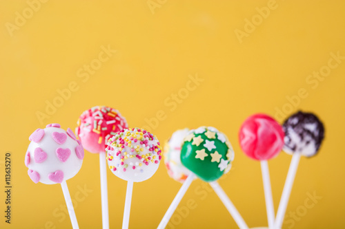 Sweet cake pops on yellow background

