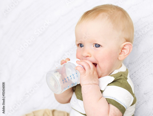 Baby drinking water on a couch
