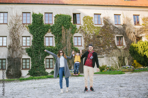 Happy young family, father and mother keep son's hands outdoors