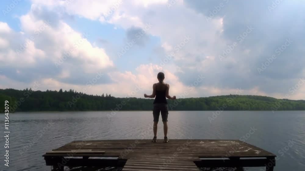 Young woman standing on the pier with arms outstretched
Young woman standing on the pier with arms outstretched