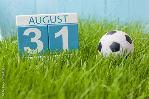 August 31st. Image of august 31 wooden color calendar on green grass lawn background with soccer ball. Summer day. Empty space for text