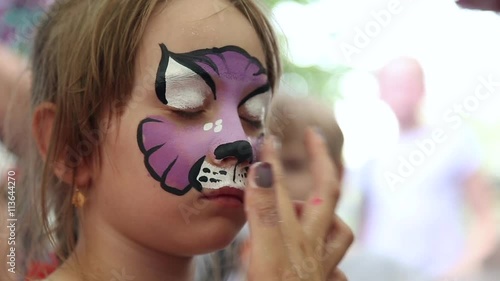 The artist paints face painting on the face of the girl

